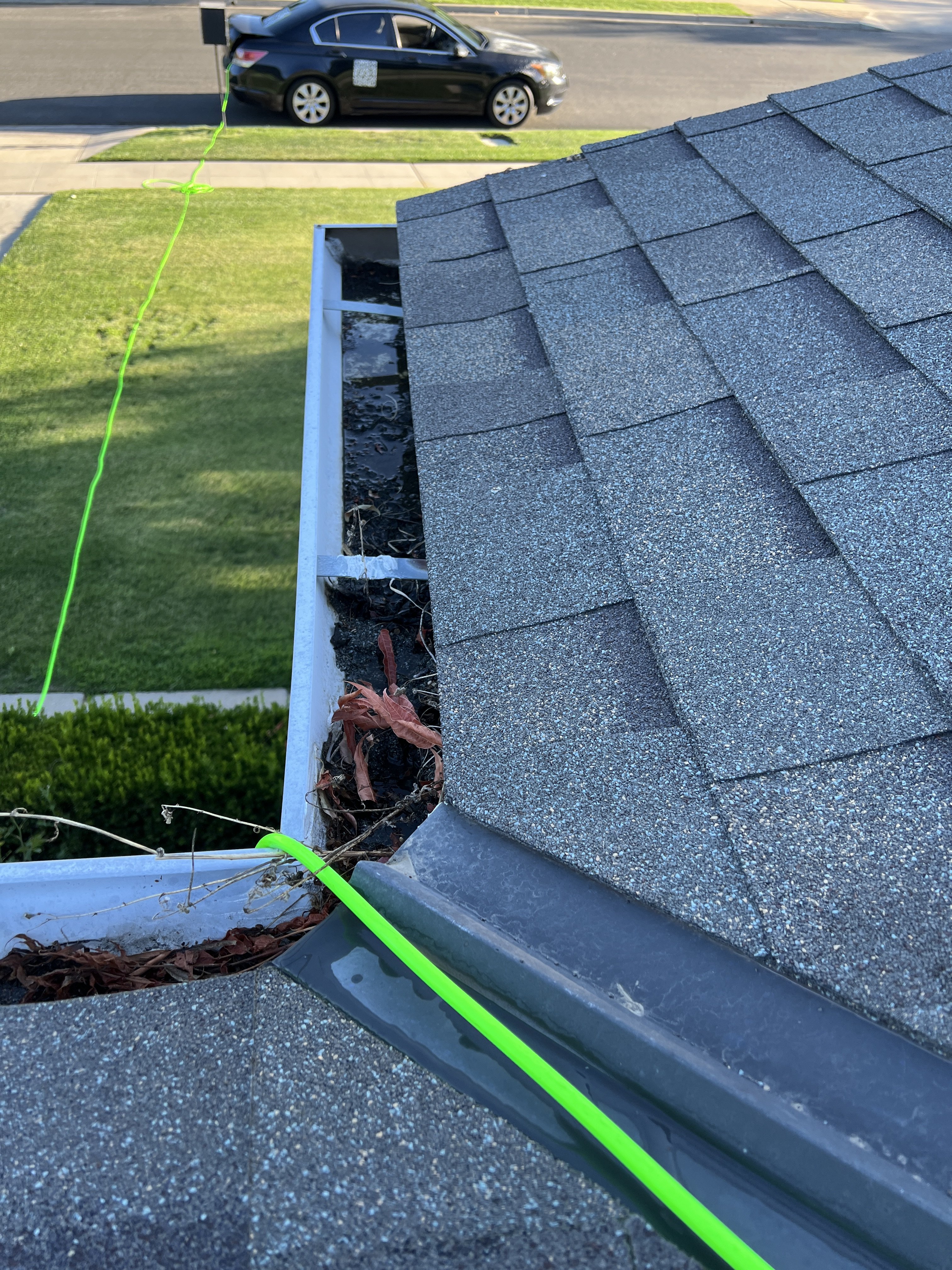 Technician cleaning clogged gutters on residential roof in Fresno, CA