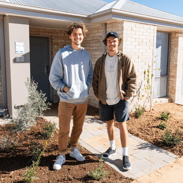 Homeowners smiling in front of a new Perth custom home exterior, celebrating their completed project