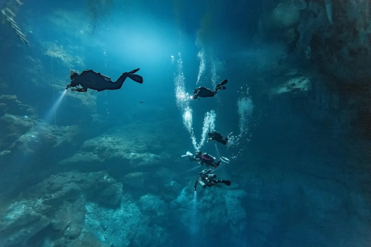 Scuba diver descending into the deep blue waters of El Pit