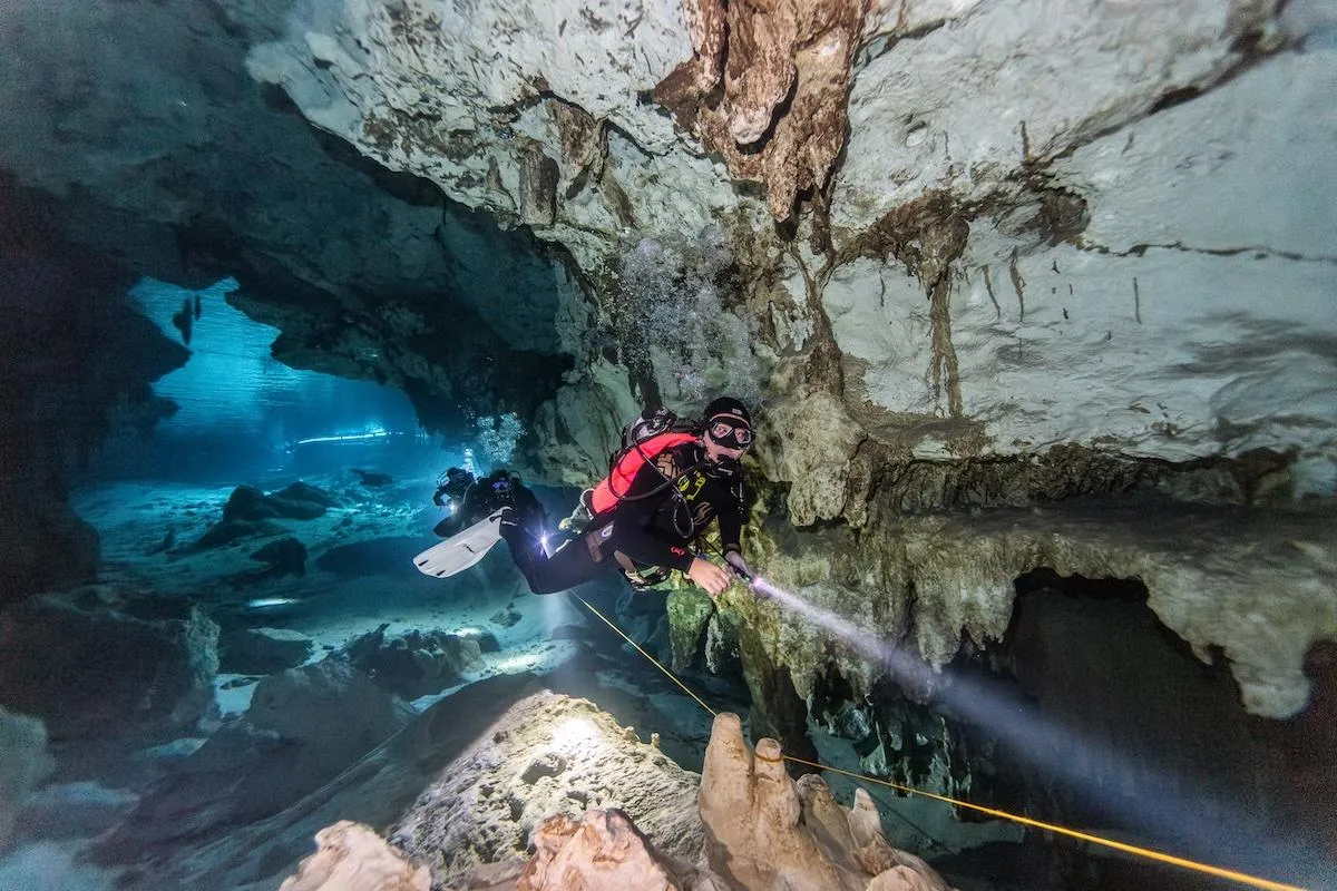 Scuba divers exploring stalactites inside Dos Ojos cenote cavern