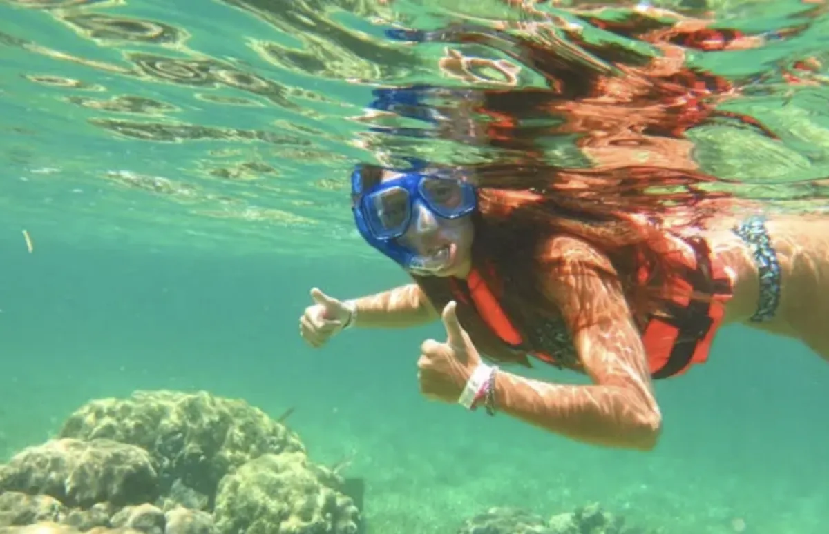 snorkeler underwater with thumbs up