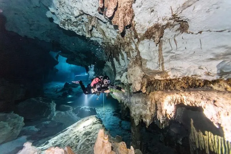 Scuba diver exploring the impressive limestone formations in Dos Ojos cenote near Tulum