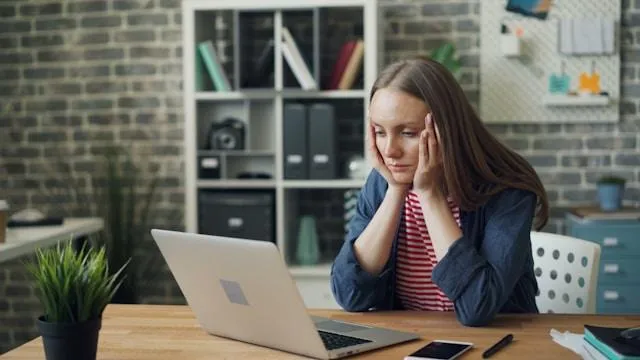 Woman stressed while sitting at a desk and looking at her laptop