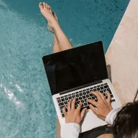 woman beside pool using laptop