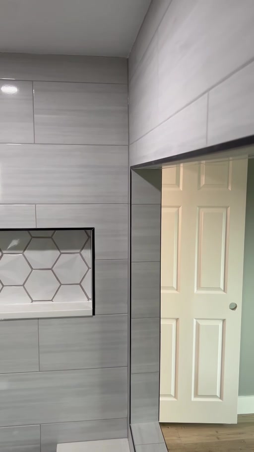 Gray shower tile with a recessed mosaic niche