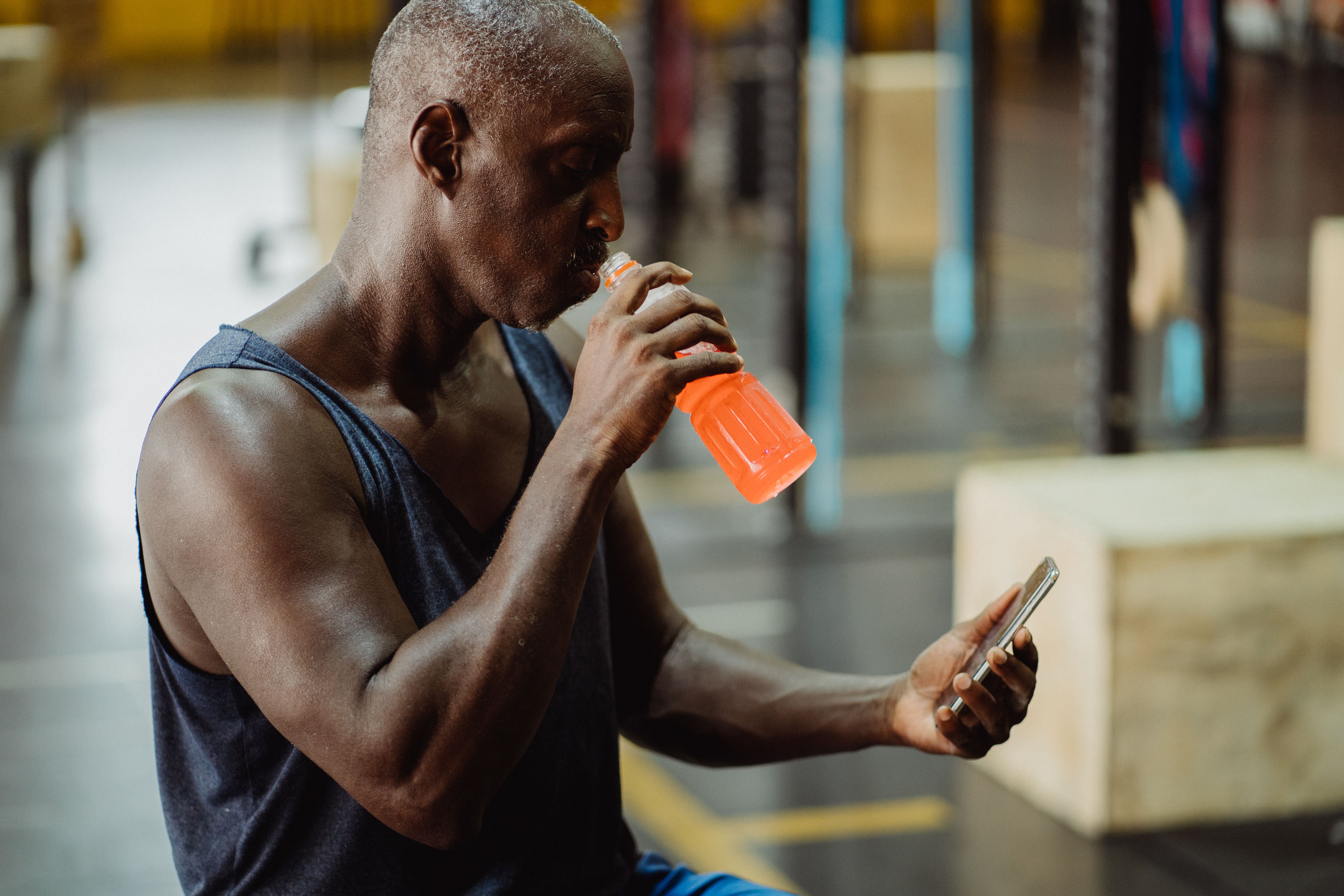 man looking at phone and drinking out of water bottle