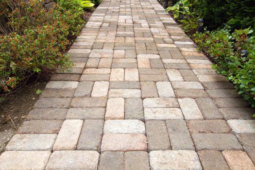 Brick paver walkway bordered by greenery, highlighting professional paver installation.