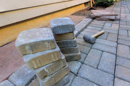 Stack of pavers and tools on a brick walkway under construction.