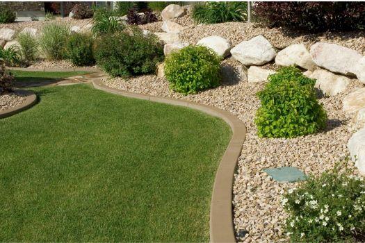 Lawn with a curved concrete border and decorative rocks, highlighting professional landscaping.