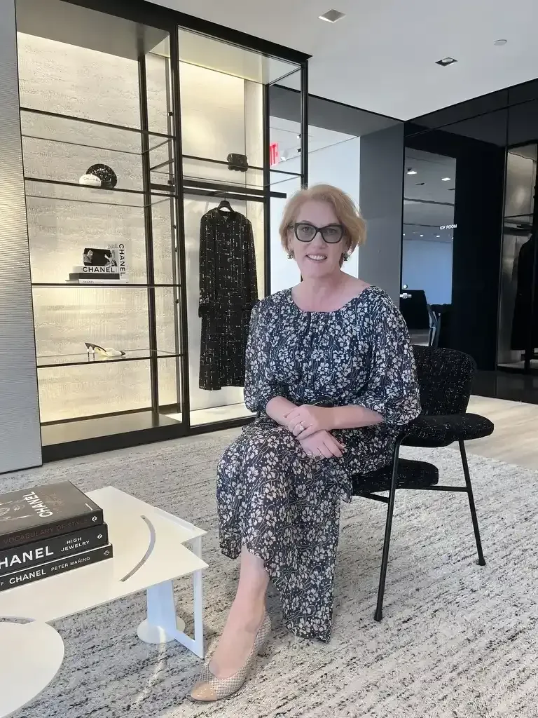 Stylish woman in patterned clothing sitting in a modern luxury office space.