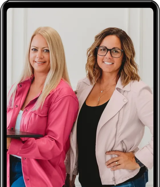 Two female business mentors standing side-by-side in pink jackets, smiling and confident.