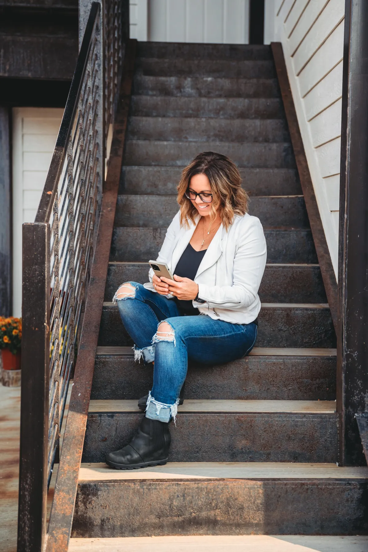 Natasha Roberson smiling confidently in an orange blazer, standing on a bright porch with a laptop in hand