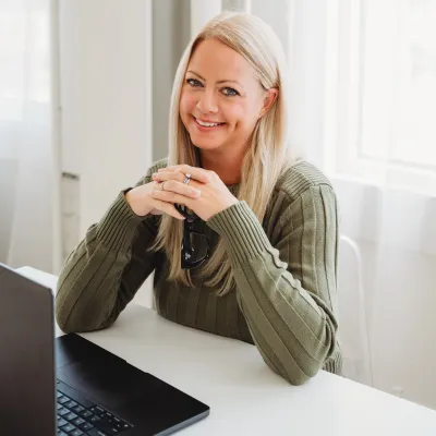 Woman on a couch with laptop on her lap, smiling and talking on the phone — text overlay: "Niche Like a Boss"