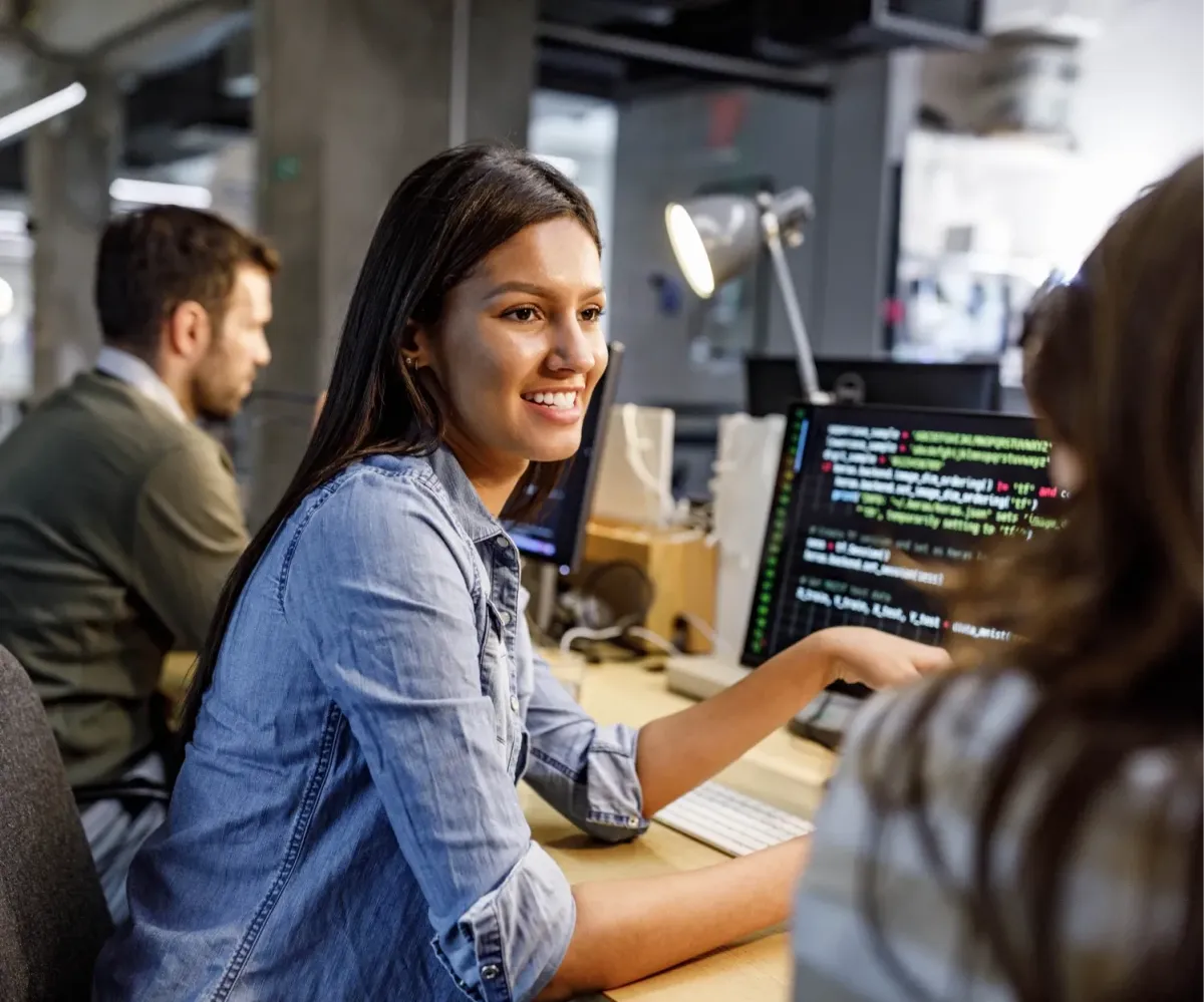 Woman developer working on computer with code in a collaborative office environment