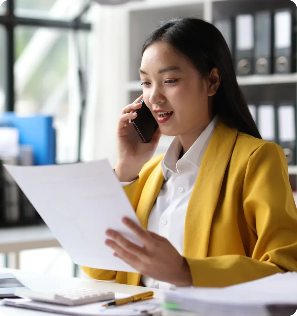 Woman handling administrative work while talking on phone and reviewing documents