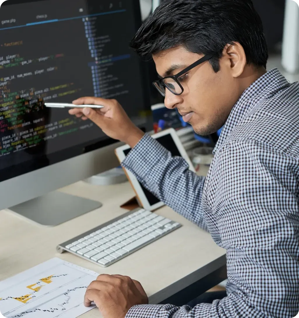 Software developer coding on computer with multiple screens in workspace