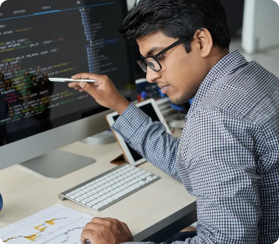 Software developer coding on computer with multiple screens in workspace