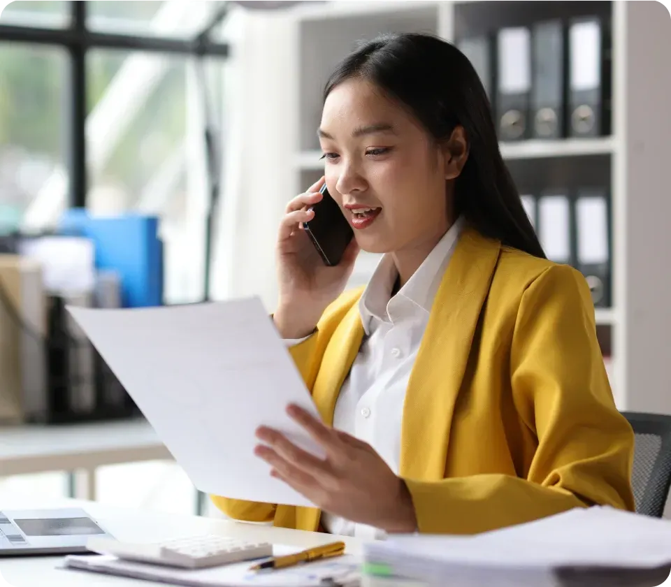 Woman handling administrative work while talking on phone and reviewing documents