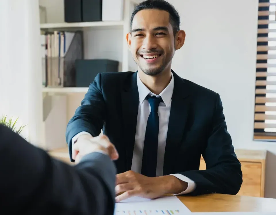 Business professional shaking hands during meeting to confirm partnership or hiring agreement
