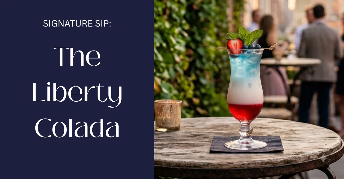 Two Liberty Colada cocktails with red, white, and blue layers in hurricane glasses, strawberry and blueberry garnish, fresh mint, on a white linen table in summer light