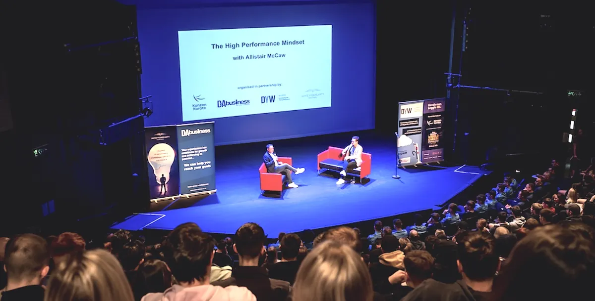 Jamie McBrearty speaking on stage at a high-performance mindset event with an audience.