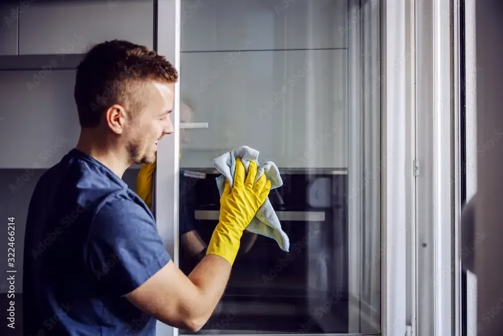 Professional cleaner wearing gloves wiping glass door – residential and commercial cleaning services in Australia