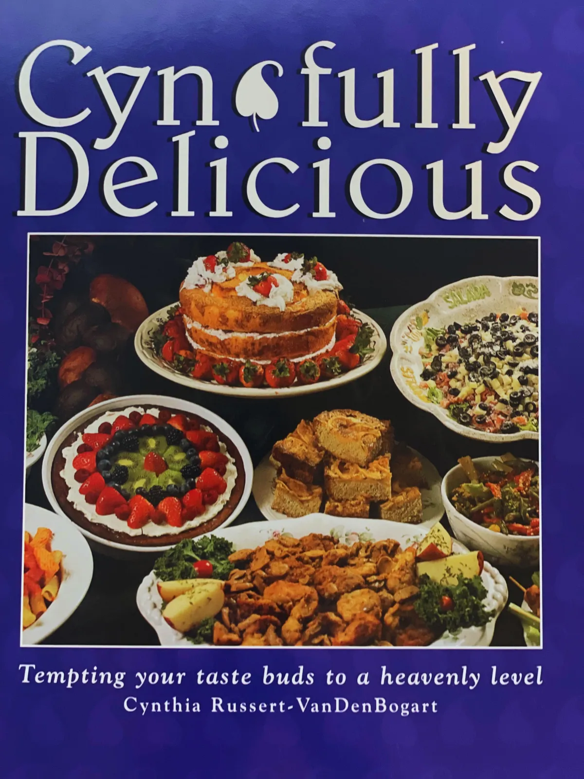 Cover of Cyn-fully Delicious (2002) cookbook featuring food dishes on a deep blue background 