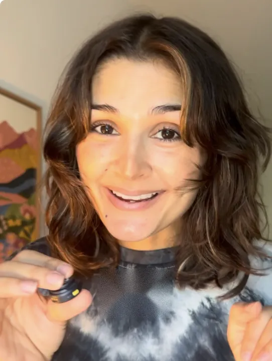 Relaxed salon owner smiling peacefully in a bright, modern beauty studio holding an iced coffee