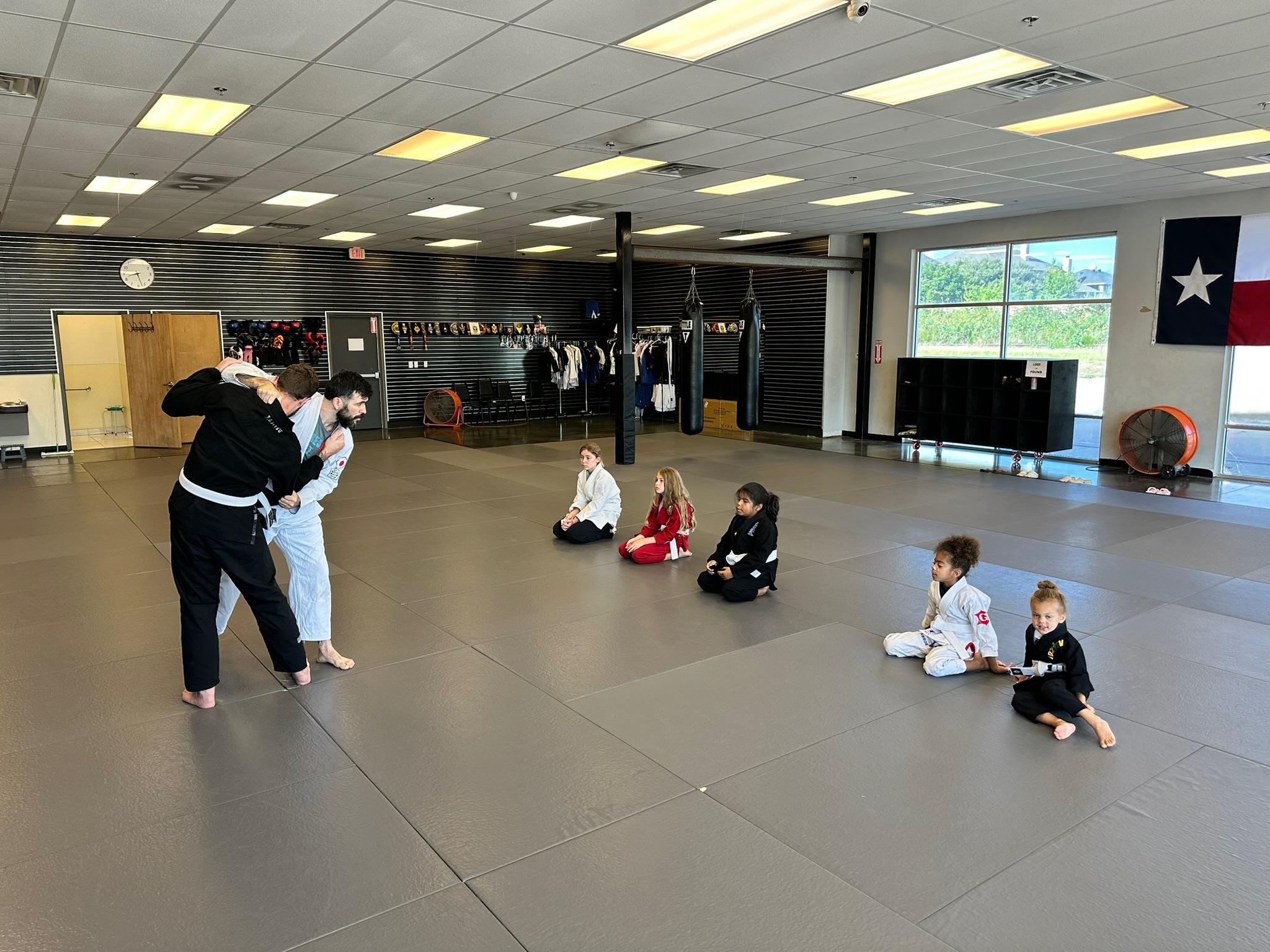 Coach teaching a Judo throw to a young student