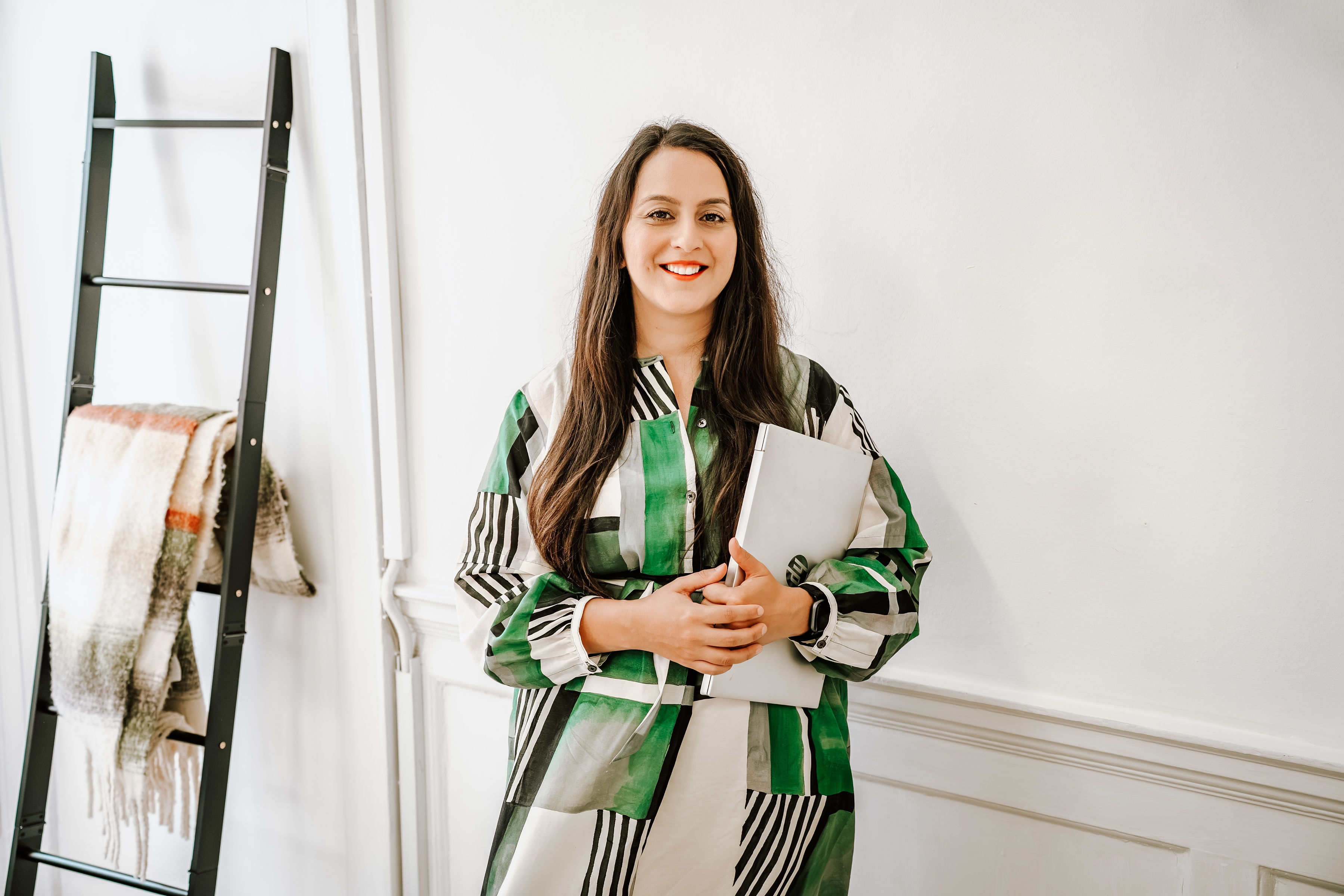 Dr Sara Schamborg, practitioner psychologist and EMDR practitioner, smiling and holding a laptop in a bright Bristol therapy room