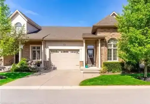 Modern brick residential house with attached garage, arched windows, and well-maintained front greenery.