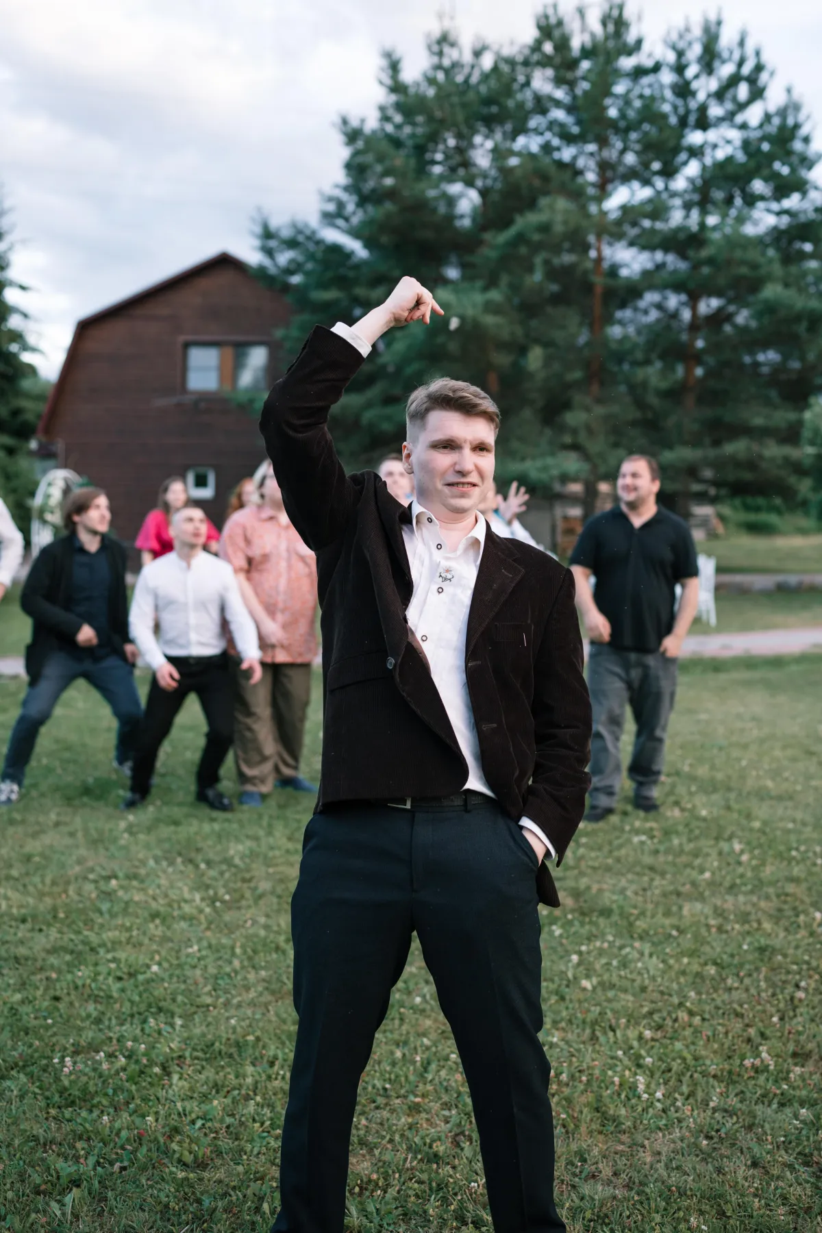 A groom tossing the garter in an open field with excited groomsmen ready to catch it, capturing a classic wedding tradition in a photo-worthy moment using the glambot style glam drone.