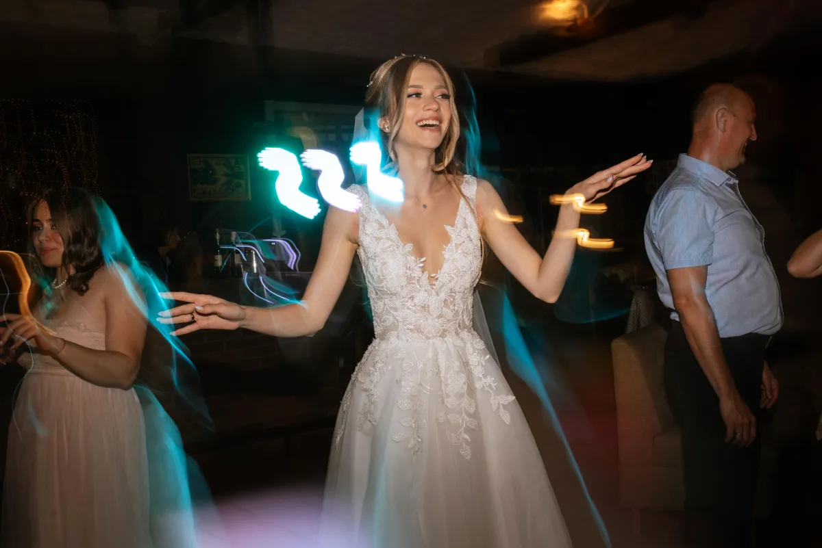 A bride twirls on the dance floor as dynamic lighting effects enhance the celebration, showcasing an electrifying DJ experience.