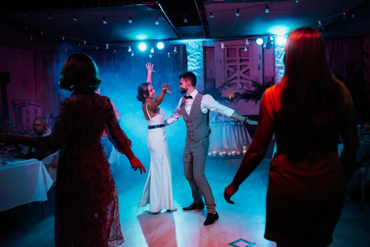 Bride and groom dancing at a wedding reception with professional DJ lighting and a lively atmosphere, created by Dynamic Celebrations