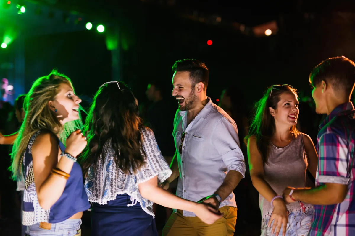 Guests enjoying a lively outdoor wedding reception in San Antonio with vibrant lights, music, and dancing under the night sky.