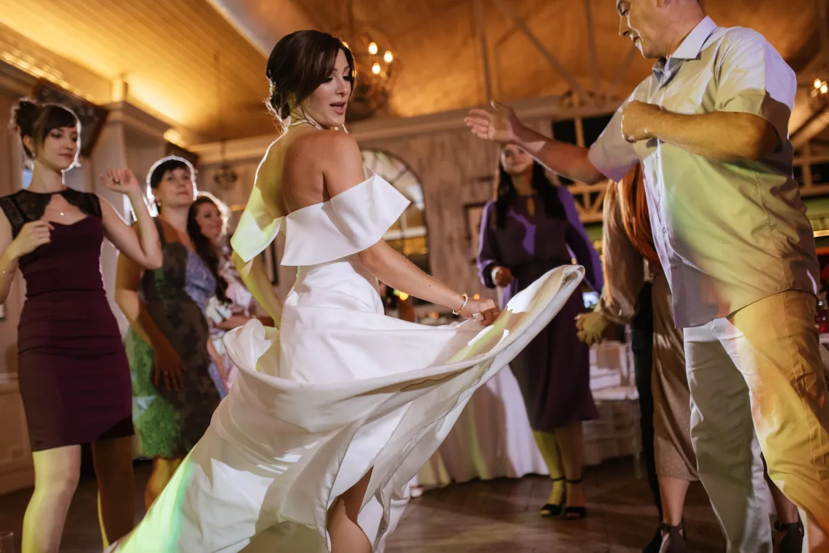 Bride dancing at a wedding reception with guests, enjoying live DJ entertainment and a vibrant celebration by Dynamic Celebrations.