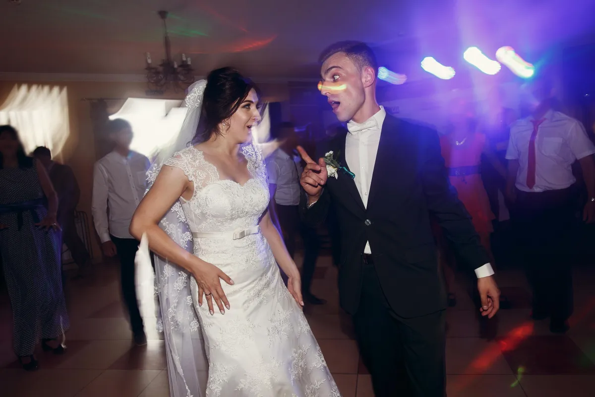 A joyful moment between newlyweds as they dance under vibrant DJ lights, bringing excitement and energy to their special day.