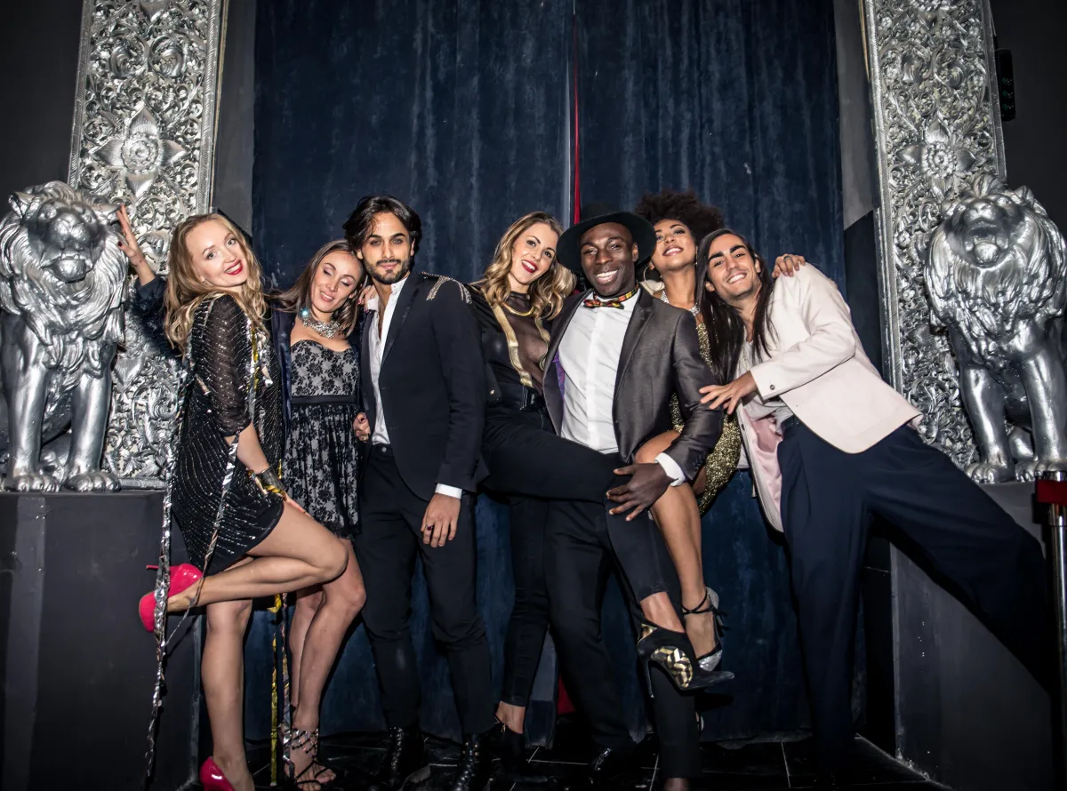 A group of well-dressed guests posing at an upscale photo booth with an elegant, silver and navy blue-themed background. Perfect for black-tie events, weddings, and luxury parties in Austin and College Station.