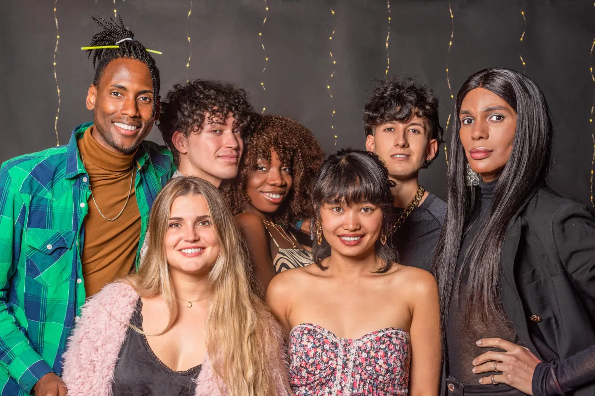 A diverse group of stylish young adults posing together in a trendy black-and-gold-lit photo booth, showcasing the ultimate party experience with a modern backdrop.