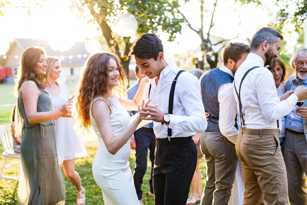 Elegant outdoor wedding reception in College Station – a joyful couple dances under the golden sunset, surrounded by friends and family celebrating in a scenic venue