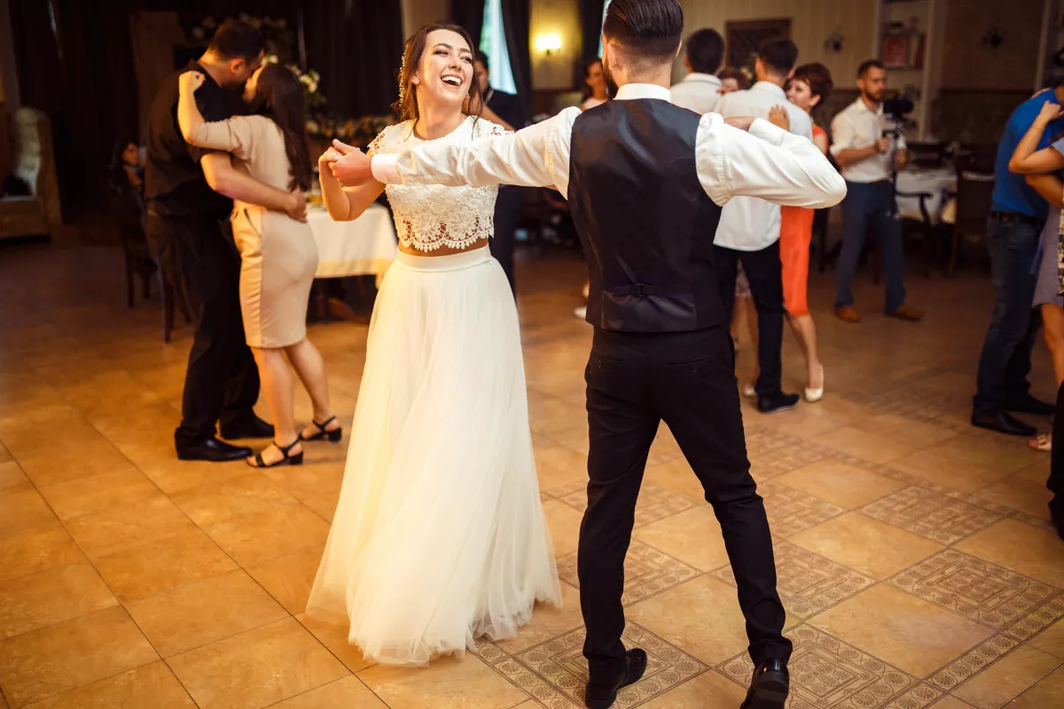 Bride and groom joyfully dancing at a lively Fort Worth wedding reception, surrounded by guests celebrating their big day.