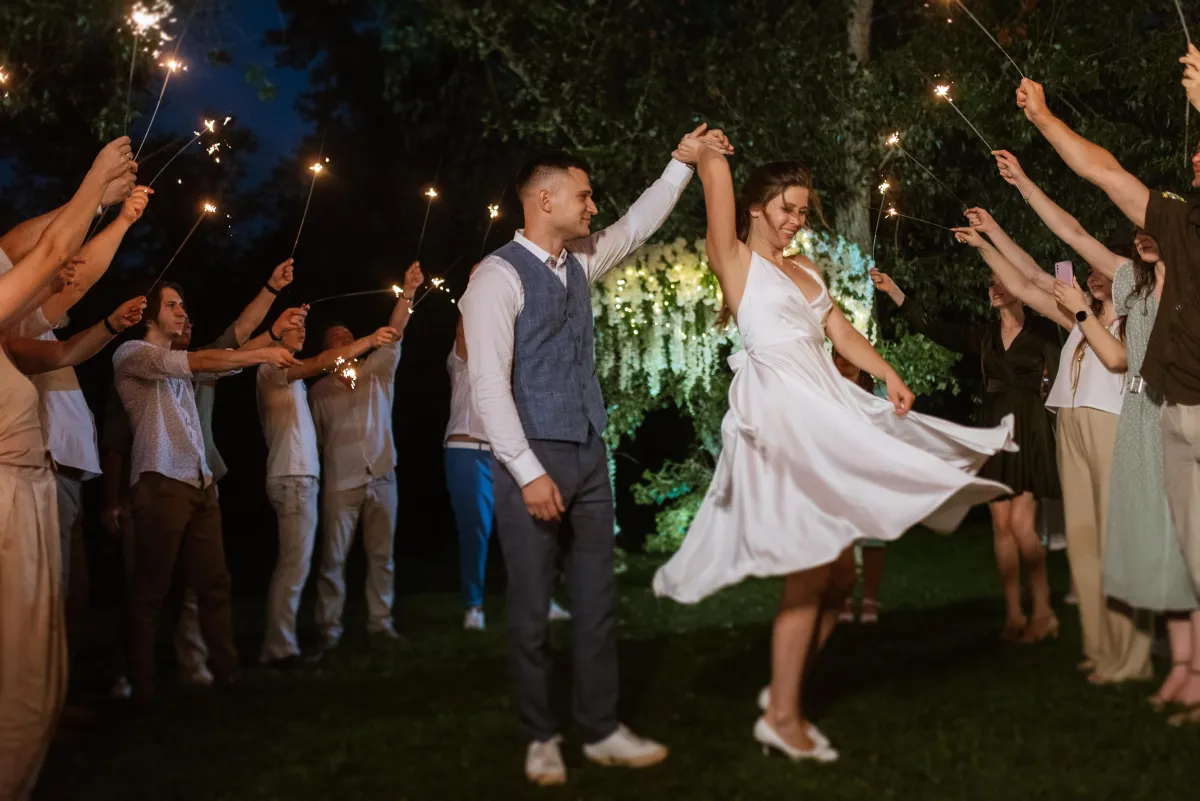 A bride and groom share a magical dance under sparklers, surrounded by cheering guests, highlighting the unforgettable wedding DJ experience.