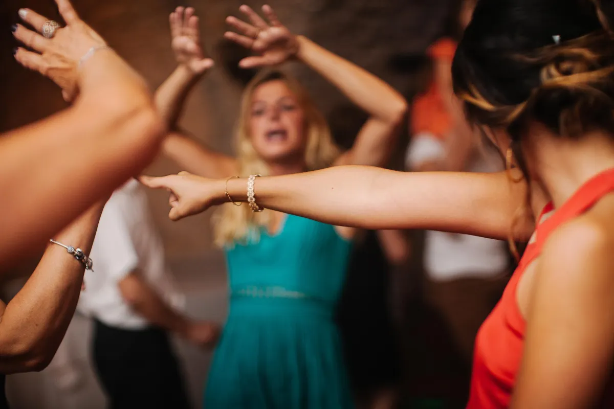 Guests on the dance floor raise their hands and cheer, showcasing an electric and joyful party vibe.