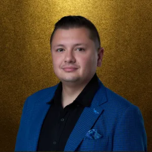 A professional headshot of David Ray Cross Jr., CEO of Dynamic Celebrations, wearing a stylish blue jacket against a gold backdrop, representing leadership and excellence in the event industry.