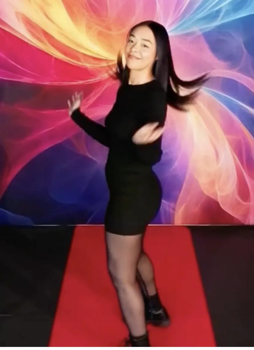 Woman posing on a red carpet in front of a colorful abstract photo booth backdrop at an event.