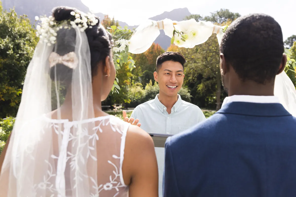 Outdoor wedding ceremony with a smiling officiant leading the vows for a couple in Houston, Dallas, Austin, or San Antonio.