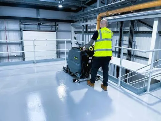 Industrial hard-floor cleaning with a ride-on scrubber in a commercial plant area