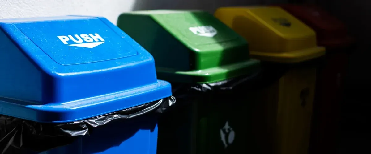 Overflowing trash and recycling bins with bags and cardboard