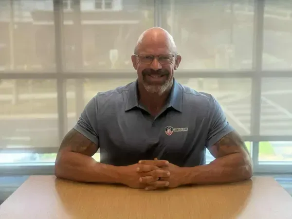 Smiling Liberty Bins owner of a trash bin cleaning company seated at a desk in a bright office.