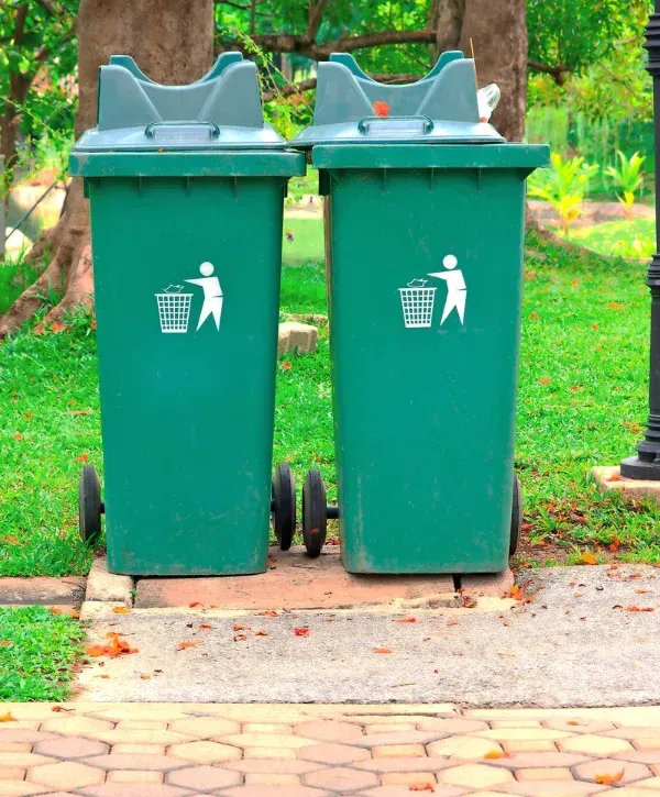 Green trash bins in a clean park environment promoting proper waste disposal.